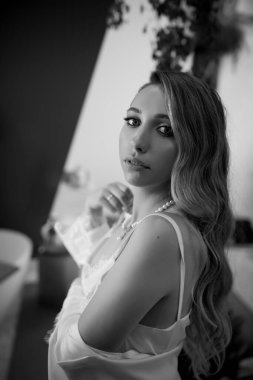 Düğün saç stili ve makyajlı güzel gelin sabahları kameraya bakıyor.