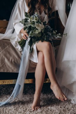 Güzel gelinin buketi tutarken ve evde otururken çekilmiş bir fotoğrafı. 