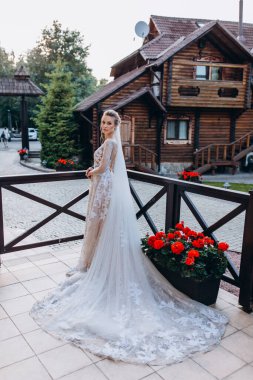 Gelinlik ve duvak içinde terasta poz veren mutlu genç gelin