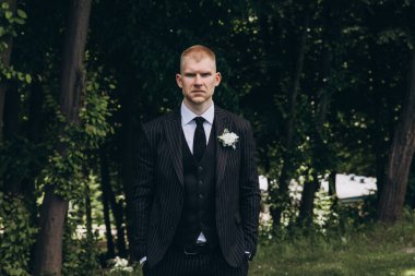 Parkta poz veren gelinlik giymiş genç bir adamın portresi.