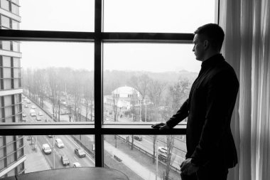 Yakışıklı genç adam şehirde vitrinde poz veriyor.