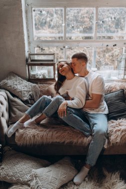 Sevgili çift pencerenin yanındaki kanepede flört ediyor. 