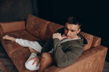 Kanepede dinlenen dalgın genç adamın yüksek açılı görüntüsü