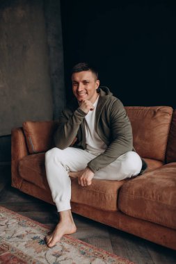 Kanepede dinlenen rahat elbiseli mutlu genç adam.