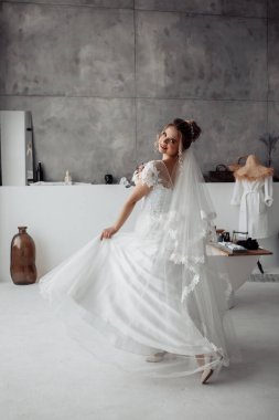 Duvağı banyoda poz veren beyaz elbiseli güzel gelin.