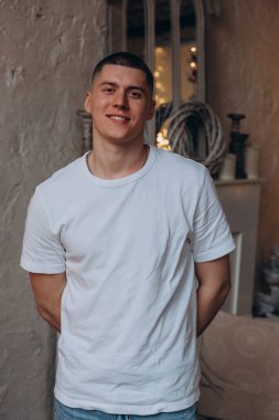 Beyaz tişörtlü, kameraya gülümseyen yakışıklı genç adamın portresi. 