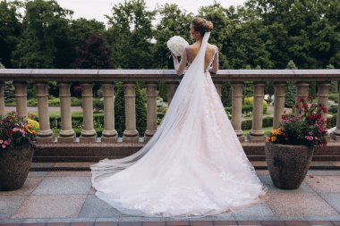 Zarif gelinlik içinde, elinde bir buket çiçekle güzel bir gelin.                      