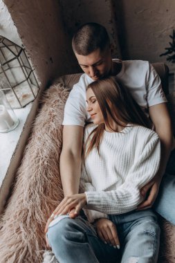 Mutlu çift pencerenin yanındaki kanepede yatıyor. 