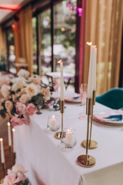 Düğün resepsiyonunda mumlar ve çiçeklerle güzel bir masa.                