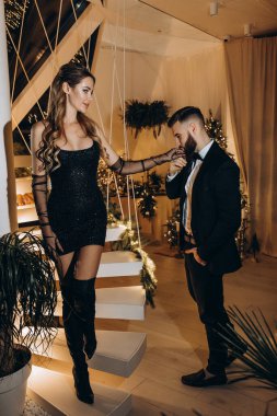 Merdivenlerde poz veren zarif bir çift. Adam kadınların elini öpüyor. 