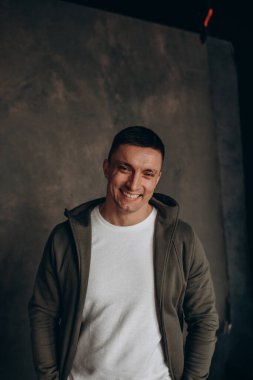 Beyaz tişörtlü yakışıklı adam gri arka planda.