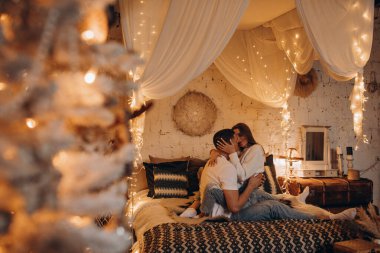 Aşık çift yatak odasında çelenk ışıklarıyla eğleniyor. 