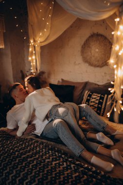 Aşık çift yatak odasında çelenk ışıklarıyla eğleniyor. 
