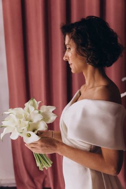 Zarif gelinlik içinde, elinde bir buket çiçekle güzel bir gelin.                      