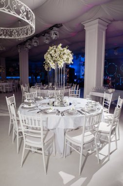 Beyaz sandalyeli ve çiçekli güzel bir masa.