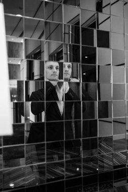 Aynanın yanında poz veren takım elbiseli genç iş adamı 