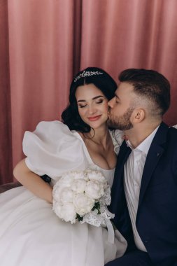 Mutlu bir çift stüdyoda oturup öpüşüyor.