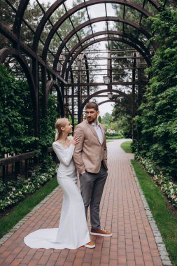 Mutlu genç gelin ve damat parkta birlikte poz veriyorlar.. 