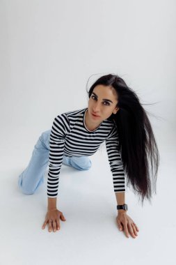 Gri arka planda poz veren çekici esmer kadın.. 