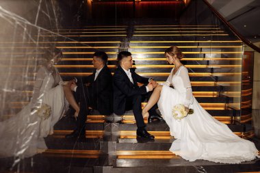 Gelin ve damat merdivenlerde oturup birbirlerine bakıyorlar.