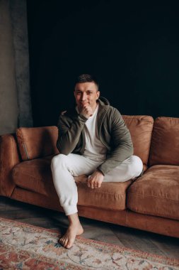 Kanepede dinlenen rahat elbiseli mutlu genç adam.