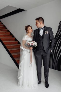 Şık gelini olan genç bir çift ve tören salonunda çiçekli bir damat.