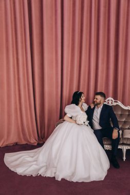 Mutlu evlilik çifti kanepede birbirlerine sarılıyorlar.