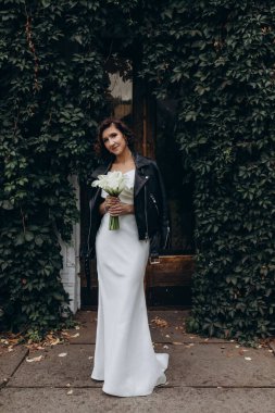 Gelinlik içinde güzel bir gelin ve açık hava buketi.