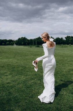 Beyaz elbiseli gelin ve tarlada duvağı olan beyaz gelinlik.