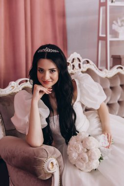 Güzel esmer gelin bir odada kanepede oturuyor..