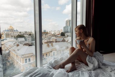 Balkonda kahve içen genç bir kadın.