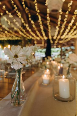 Düğün resepsiyonunda mumlar ve çiçeklerle güzel bir masa.                           
