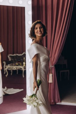 Şık elbiseler içinde, elinde düğün buketi tutan güzel bir gelin.        