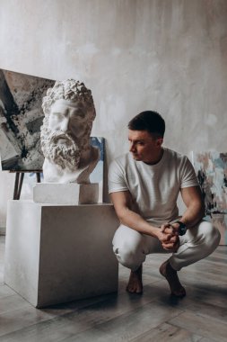 Bir erkek heykeli olan genç bir sanatçı