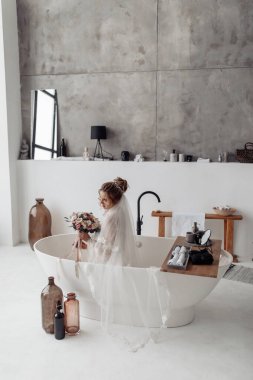 Gelin elbiseli güzel kadın banyoda oturuyor.  