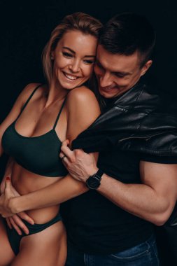 Mutlu gülümseyen beyaz çift stüdyoda kucaklaşıyor. 