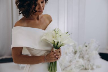 Çekici genç gelin elinde güzel bir düğün buketi tutuyor              