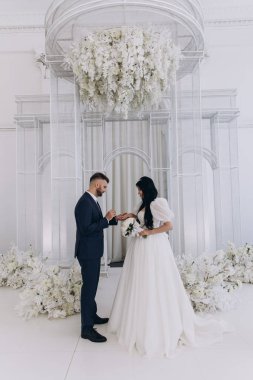 Mutlu genç gelin ve yakışıklı damat düğün töreninde el ele tutuşuyorlar.