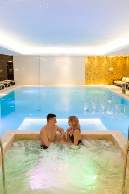 Lüks oteldeki jakuzide havuzdaki mutlu çift.