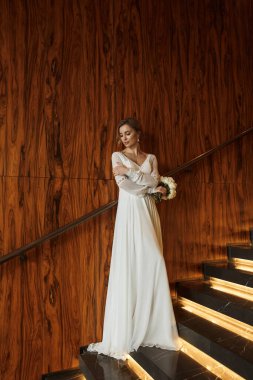 Çekici genç gelin elinde güzel bir düğün buketi tutuyor              