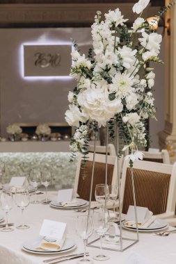 Düğün resepsiyonunda çiçeklerle süslenmiş zarif bir masa.                 