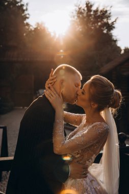 Mutlu gelin ve damat gün batımında parkta öpüşüyor. 