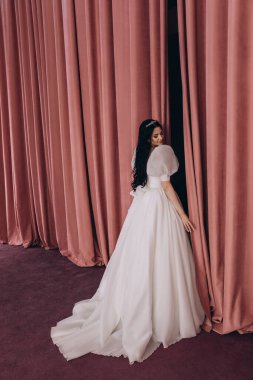 Gelinlikli güzel esmer gelin stüdyoda poz veriyor.