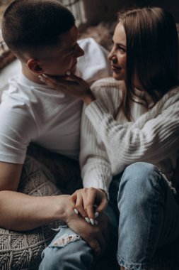 Beyaz elbiseli mutlu çift yerde oturuyor ve birbirlerine bakıyorlar.