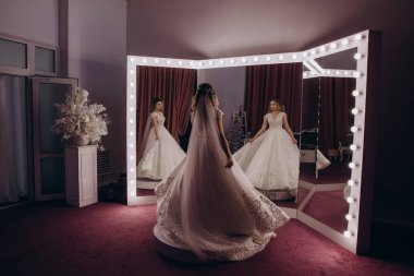 Güzel gelinin portresi. Uzun saçlı, beyaz gelinlikli, aynanın yanında. 