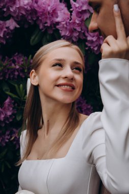 Genç aşık çift yaz parkında yürüyor, gülümsüyor, kameraya bakıyor, mutlu ve mutlu.