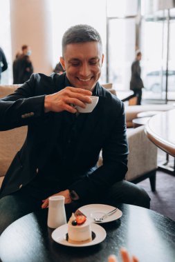 Kafedeki masada kahve içen mutlu genç adam.