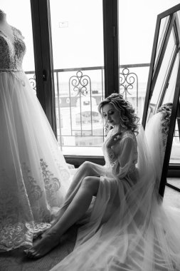 çekici genç gelin aynanın yanında oturuyor ve sabahları gelinliğe bakıyor.      