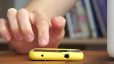 Womans hand tapping smartphone on table. Online communication and work, technologies concept. Horizontal. Front view. High quality FullHD footage