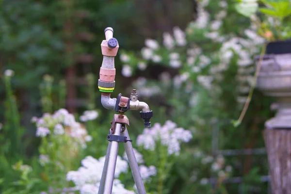 Su hortumunu bağlamak için musluğu olan eski el yapımı bahçe sulama tezgahı.                       